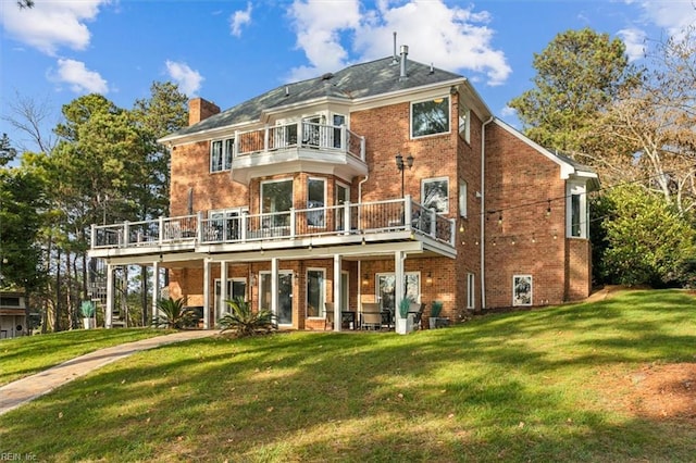 rear view of property featuring a yard, a balcony, and a deck