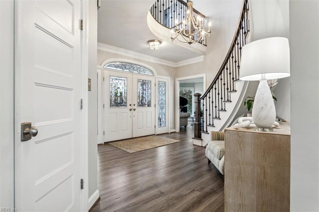 foyer entrance with crown molding, french doors, dark hardwood / wood-style floors, and a notable chandelier