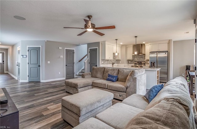 living room featuring a textured ceiling, dark hardwood / wood-style flooring, and ceiling fan