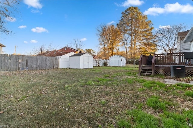 view of yard with a shed, a deck, and central air condition unit