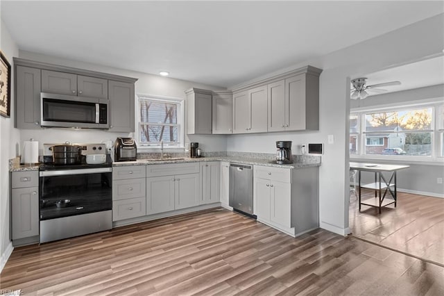 kitchen with ceiling fan, sink, light hardwood / wood-style floors, and appliances with stainless steel finishes