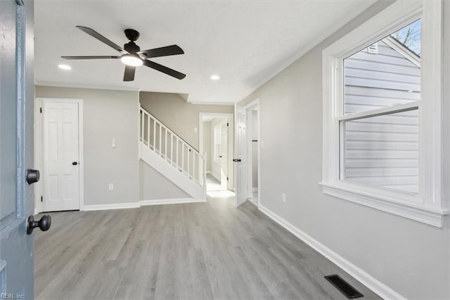 entryway with light wood-type flooring, ceiling fan, and crown molding