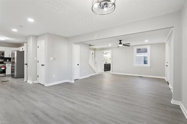 unfurnished living room featuring ceiling fan, a textured ceiling, and light wood-type flooring