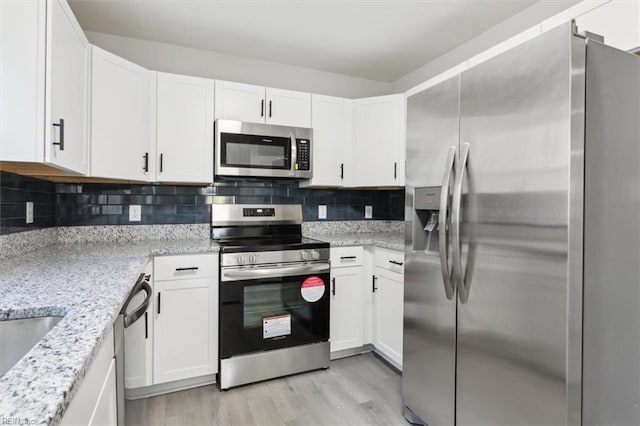 kitchen with decorative backsplash, light stone countertops, light wood-type flooring, stainless steel appliances, and white cabinetry