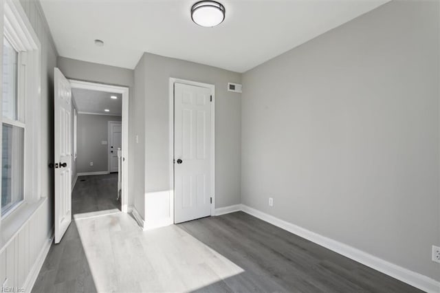 unfurnished bedroom with dark wood-type flooring and a closet