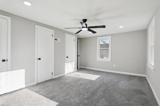 unfurnished bedroom featuring carpet floors, two closets, and ceiling fan