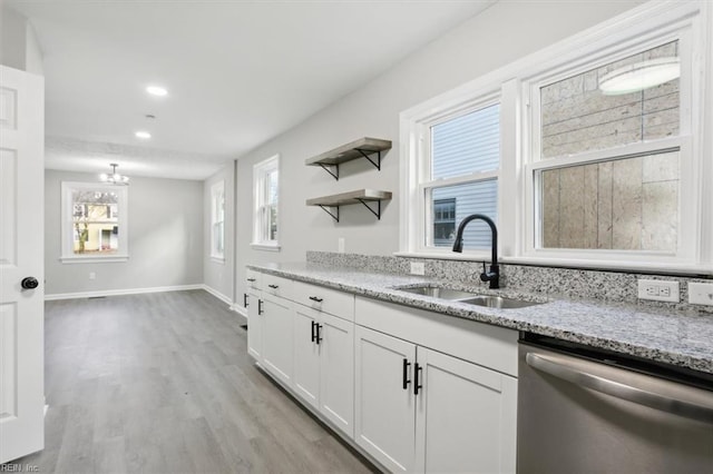 kitchen with dishwasher, sink, light stone counters, light hardwood / wood-style flooring, and white cabinets