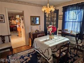 dining area featuring wood-type flooring, crown molding, and a chandelier