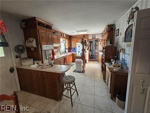 kitchen with light tile patterned flooring, kitchen peninsula, and a breakfast bar area