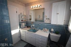 bathroom featuring vanity, toilet, and tile walls