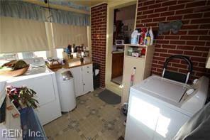 washroom featuring washer and dryer and brick wall