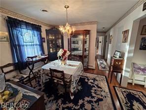 dining area with hardwood / wood-style floors, a notable chandelier, and crown molding