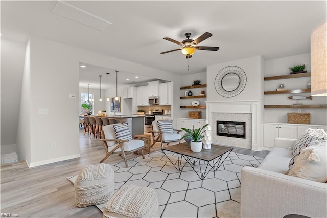 living room with ceiling fan, light hardwood / wood-style floors, sink, and a fireplace