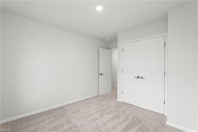 unfurnished bedroom with light carpet and a closet