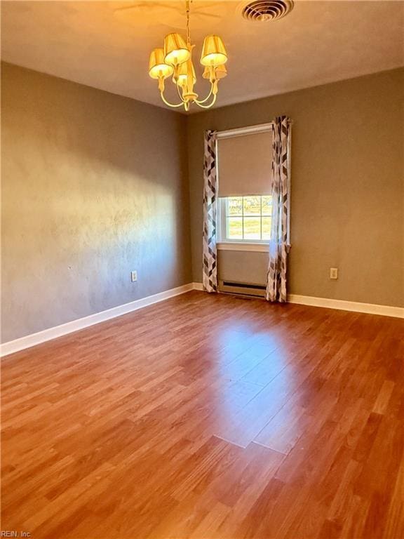 unfurnished room featuring hardwood / wood-style floors, a chandelier, and a baseboard radiator