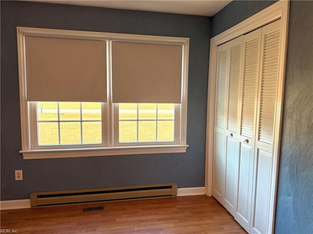 unfurnished bedroom featuring multiple windows, a closet, and baseboard heating