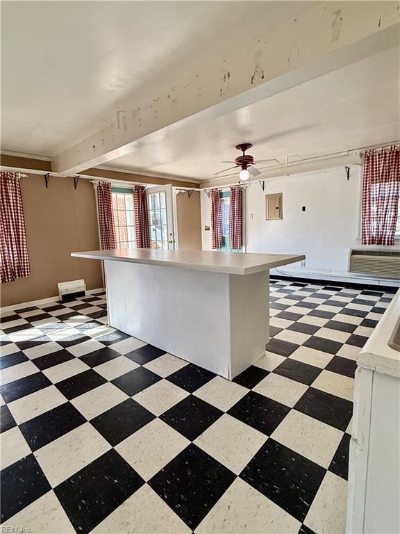 kitchen with ceiling fan, a center island, and an AC wall unit