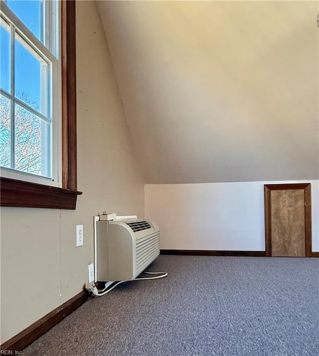 additional living space with carpet, vaulted ceiling, and a wall unit AC