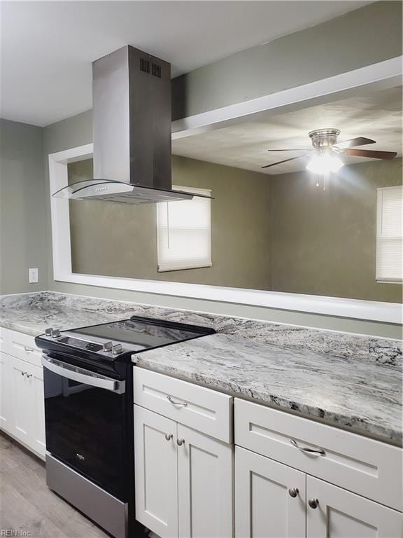 kitchen with white cabinetry, plenty of natural light, wall chimney exhaust hood, and stainless steel electric range