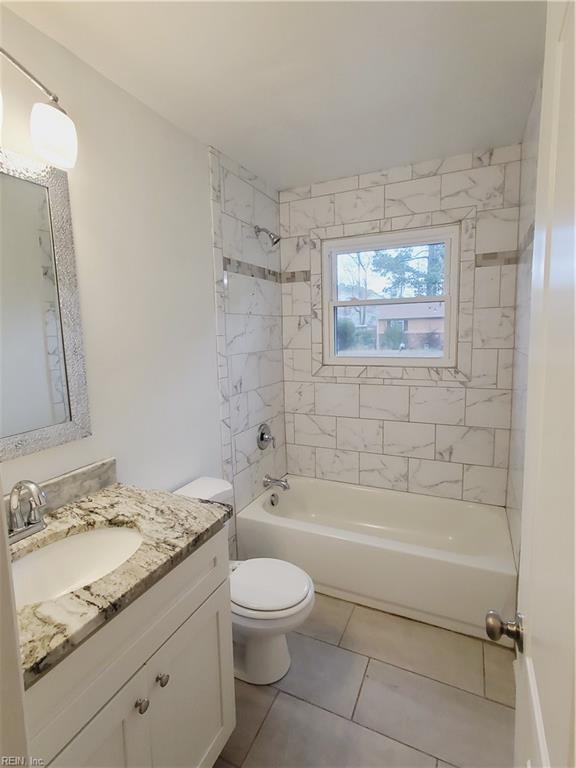 full bathroom with tile patterned floors, tiled shower / bath combo, toilet, and vanity