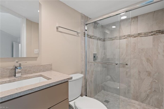 bathroom featuring vanity, toilet, and a shower with door