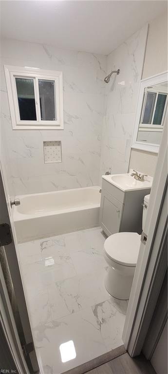 full bathroom with tiled shower / bath, vanity, and toilet