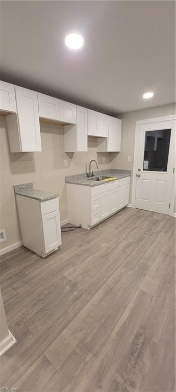 kitchen with white cabinetry, sink, and light wood-type flooring