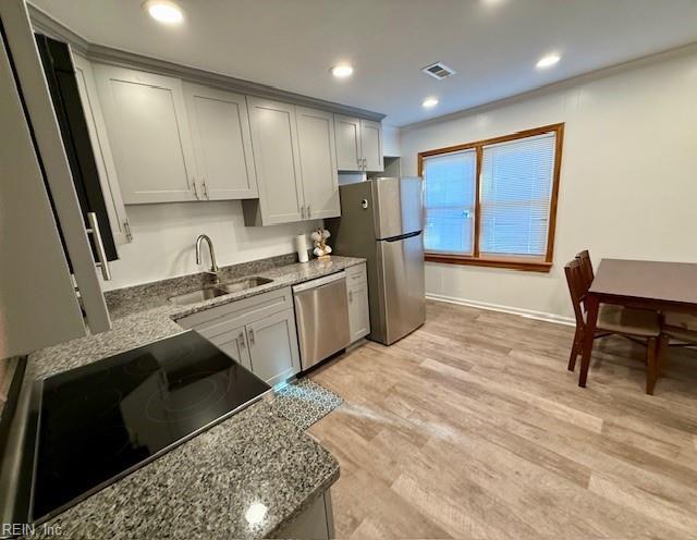 kitchen featuring stone counters, light hardwood / wood-style floors, sink, and appliances with stainless steel finishes