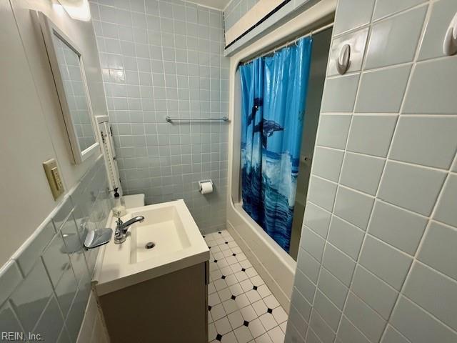 bathroom with shower / tub combo, vanity, and tile walls