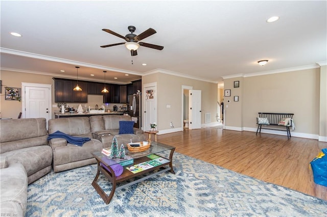 living room with hardwood / wood-style floors, ceiling fan, and crown molding