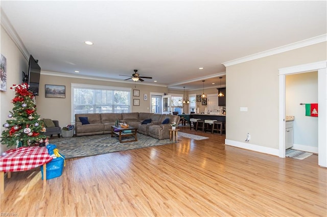 living room with light hardwood / wood-style flooring, ceiling fan, and ornamental molding