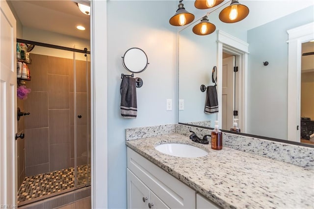 bathroom featuring a shower with door and vanity