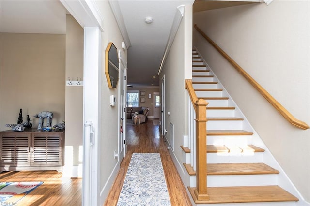 stairway featuring wood-type flooring and ornamental molding