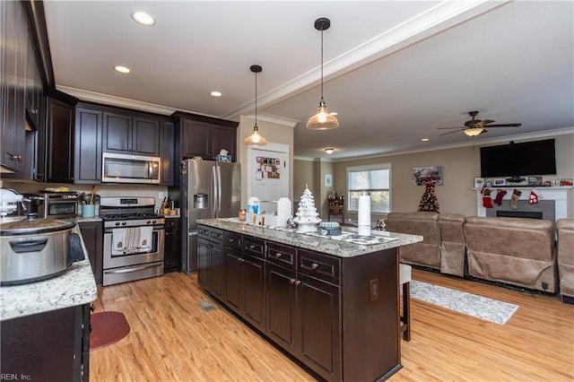 kitchen featuring stainless steel appliances, light hardwood / wood-style flooring, pendant lighting, a breakfast bar, and ornamental molding