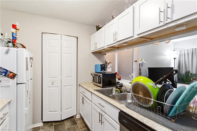 kitchen featuring a textured ceiling, white fridge, white cabinetry, and sink