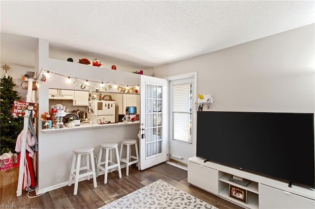 kitchen featuring kitchen peninsula, a kitchen breakfast bar, dark hardwood / wood-style flooring, a textured ceiling, and white fridge