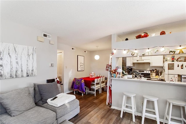 kitchen with pendant lighting, a breakfast bar, dark hardwood / wood-style floors, white fridge, and white cabinetry