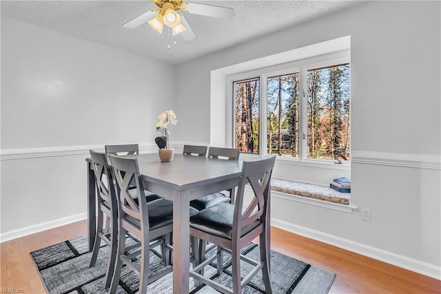 dining space featuring ceiling fan, wood-type flooring, and a textured ceiling