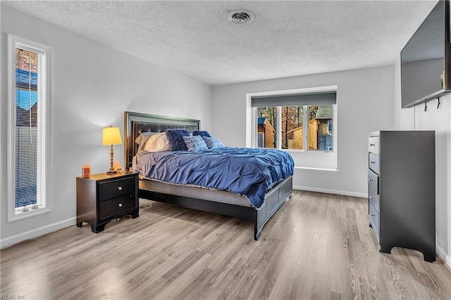 bedroom with a textured ceiling and light wood-type flooring