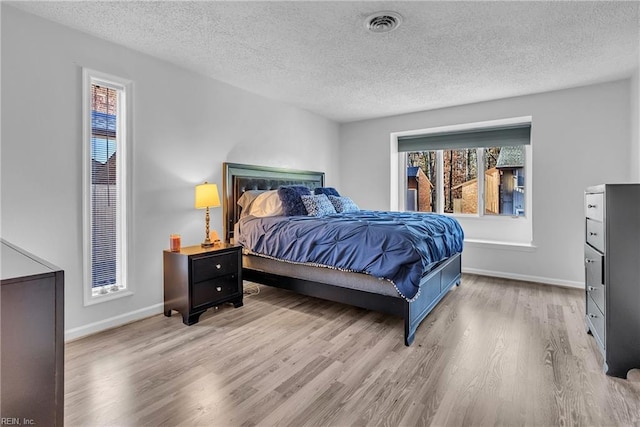 bedroom with light hardwood / wood-style floors and a textured ceiling