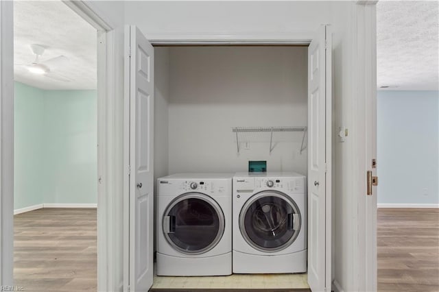 laundry area featuring a textured ceiling, washing machine and dryer, and light hardwood / wood-style floors