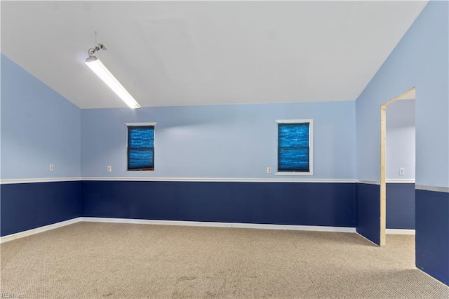 carpeted spare room with vaulted ceiling