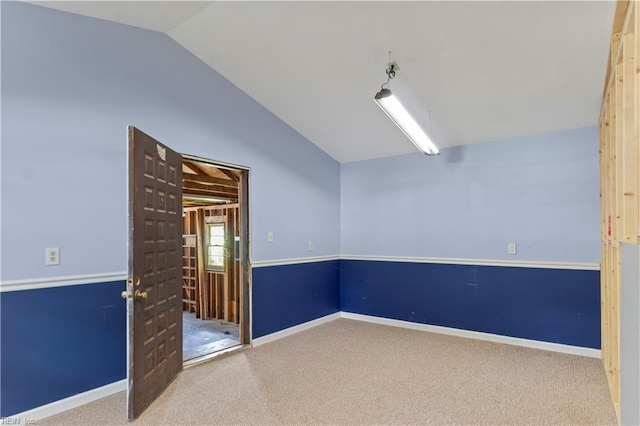 spare room featuring carpet flooring and lofted ceiling