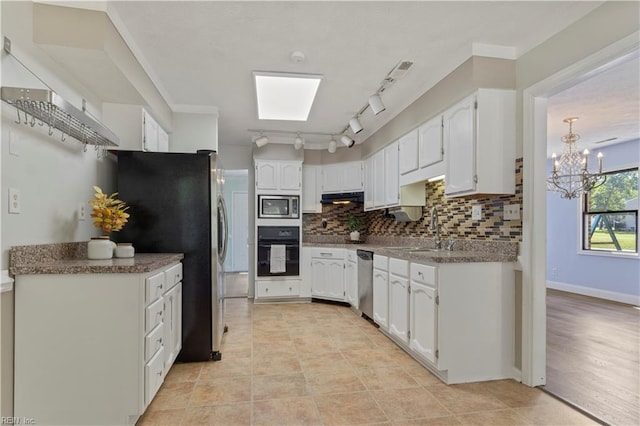 kitchen with tasteful backsplash, stainless steel appliances, sink, an inviting chandelier, and white cabinets