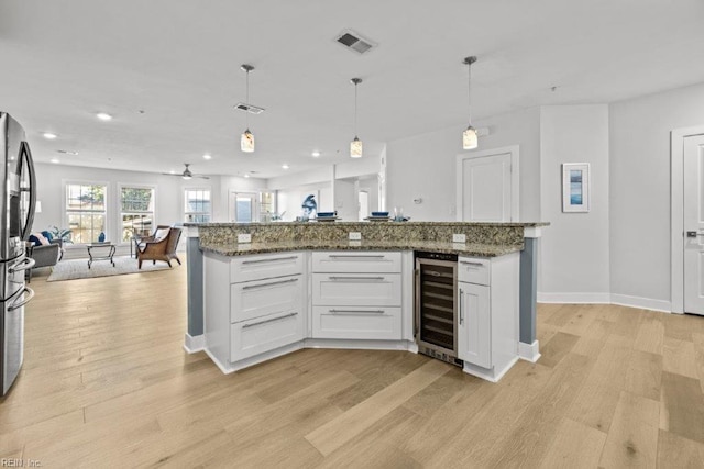 kitchen featuring light wood-type flooring, white cabinetry, hanging light fixtures, and wine cooler