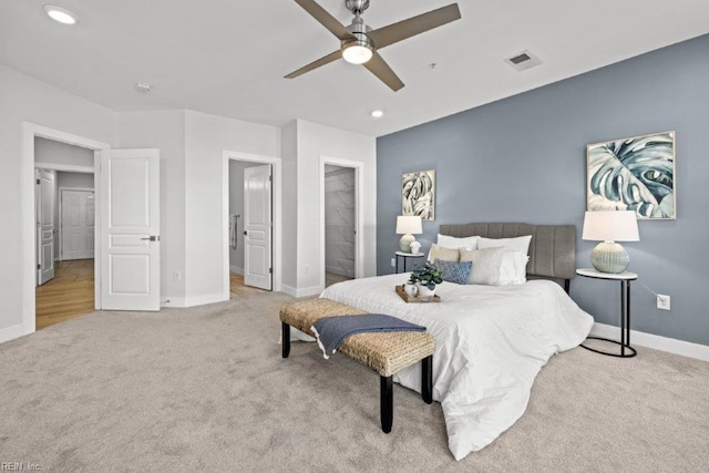 carpeted bedroom featuring a walk in closet, a closet, and ceiling fan