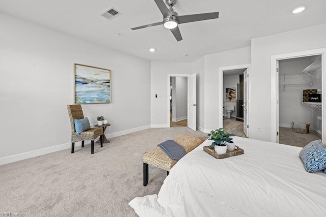 bedroom with light carpet, a walk in closet, ensuite bath, ceiling fan, and a closet