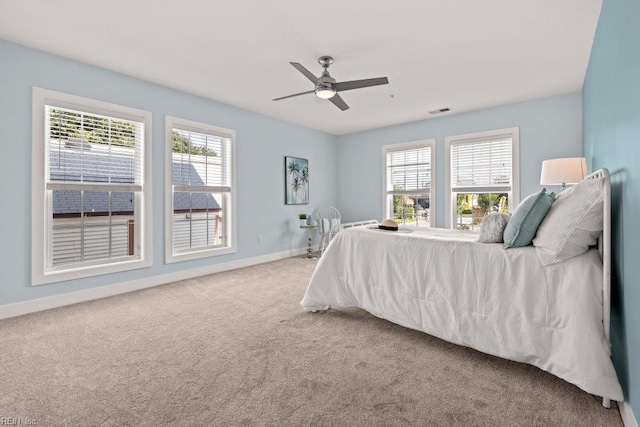 carpeted bedroom with multiple windows and ceiling fan