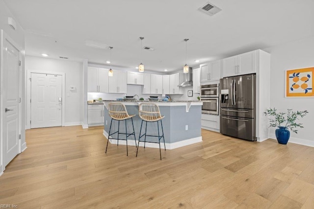 kitchen with a kitchen island with sink, appliances with stainless steel finishes, decorative light fixtures, light hardwood / wood-style floors, and white cabinetry