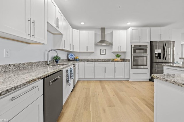 kitchen featuring white cabinetry, wall chimney exhaust hood, light wood-type flooring, and appliances with stainless steel finishes